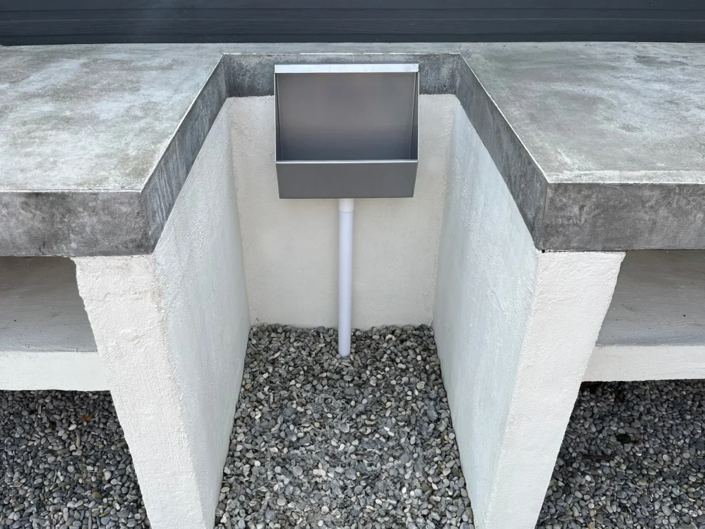 Bewerkte sfeerfoto van RVS tuinurinoir in een tuin
